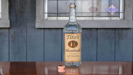 Tito's Handmade Vodka bottle with copper cap off sitting on table