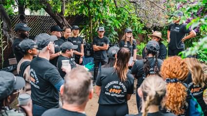 Large group of people huddled up outside wearing black Tito's Handmade Vodka t-shirts