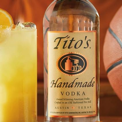 Tito's Handmade Vodka bottle and basketball next to Tito's Orange Refresher cocktail garnished with orange wheel